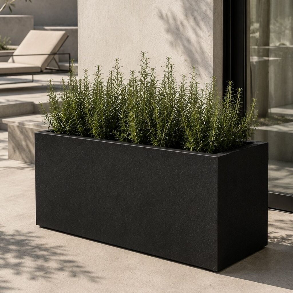 Black biopolymer planter with a green plant inside, positioned outside of a house